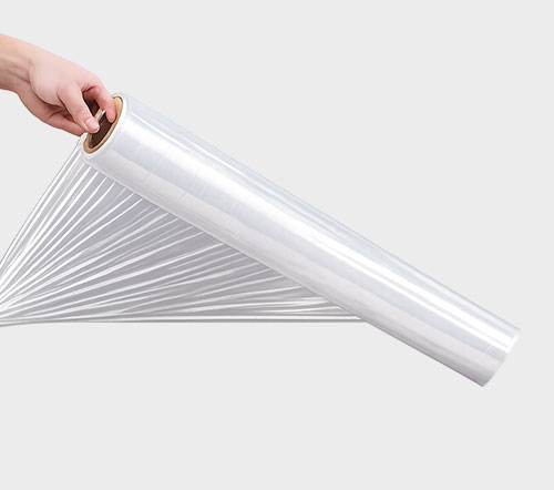 A hand holding a roll of clear plastic stretch film against a light gray background.
