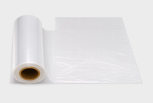 A roll of transparent plastic sheet unrolled on a surface.