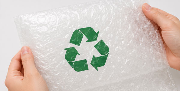 Recyclable Bubble Wrap Hands holding a sheet of bubble wrap with a green recycling symbol in the cente