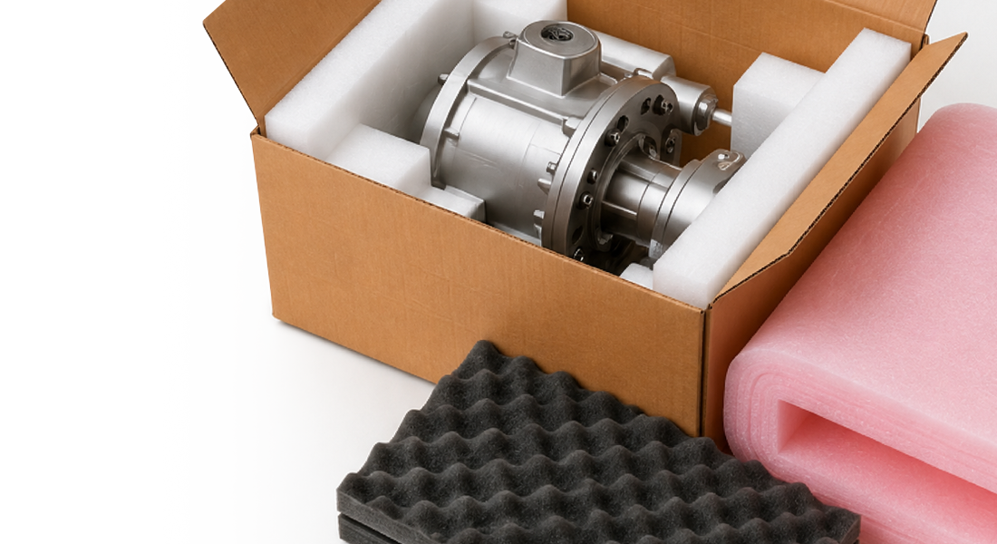 A cardboard box with a metallic component surrounded by white foam, alongside pink and black foam packing materials.