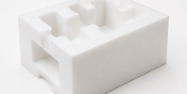 Rectangular white foam block with various cutouts.