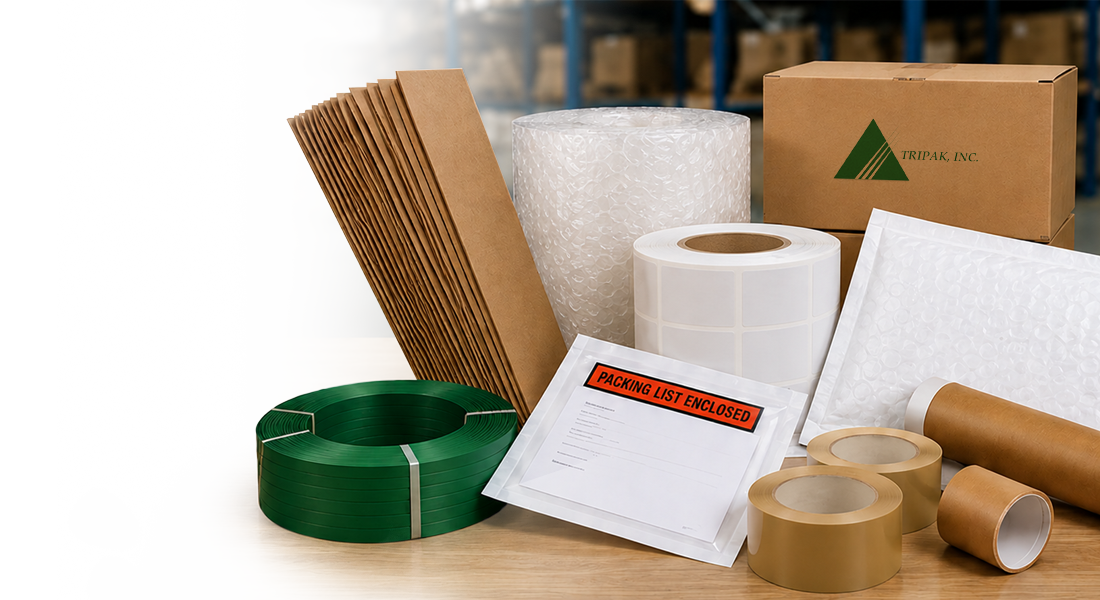 Various packaging materials including green strapping, cardboard sheets, bubble wrap, labels, padded envelopes, packing tape, and a branded box.