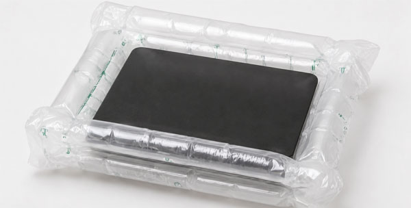 A black rectangular device in inflatable air-cushioned packaging on a light gray surface.