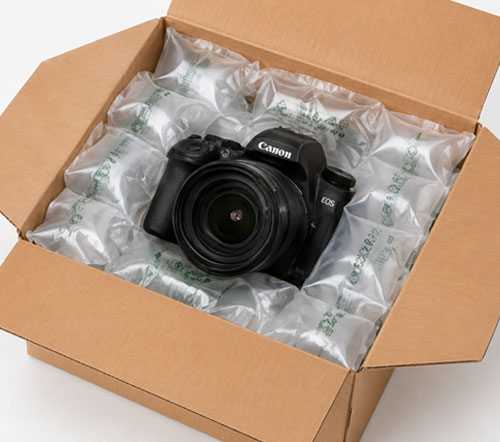 Air Pillows Open cardboard box with a Canon camera secured by air cushion packaging.
